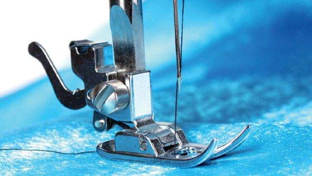 Image of presser foot of a sewing machine with black thread
