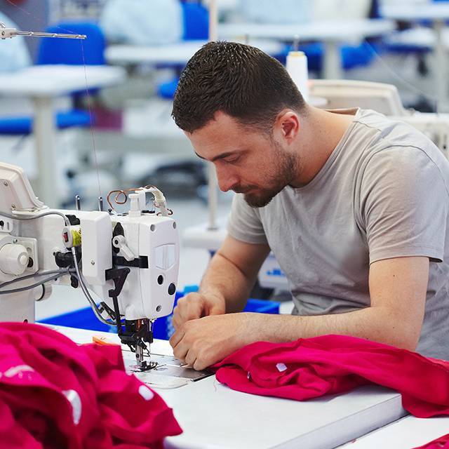 Male seamstress using sewing machine in Factory production line