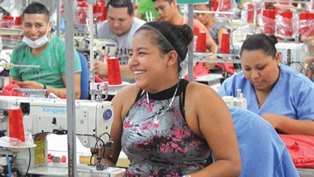 Garment worker smiling on Pinehurst manufacturing floor