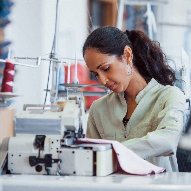 Brunette women with ponytail using sewing machine
