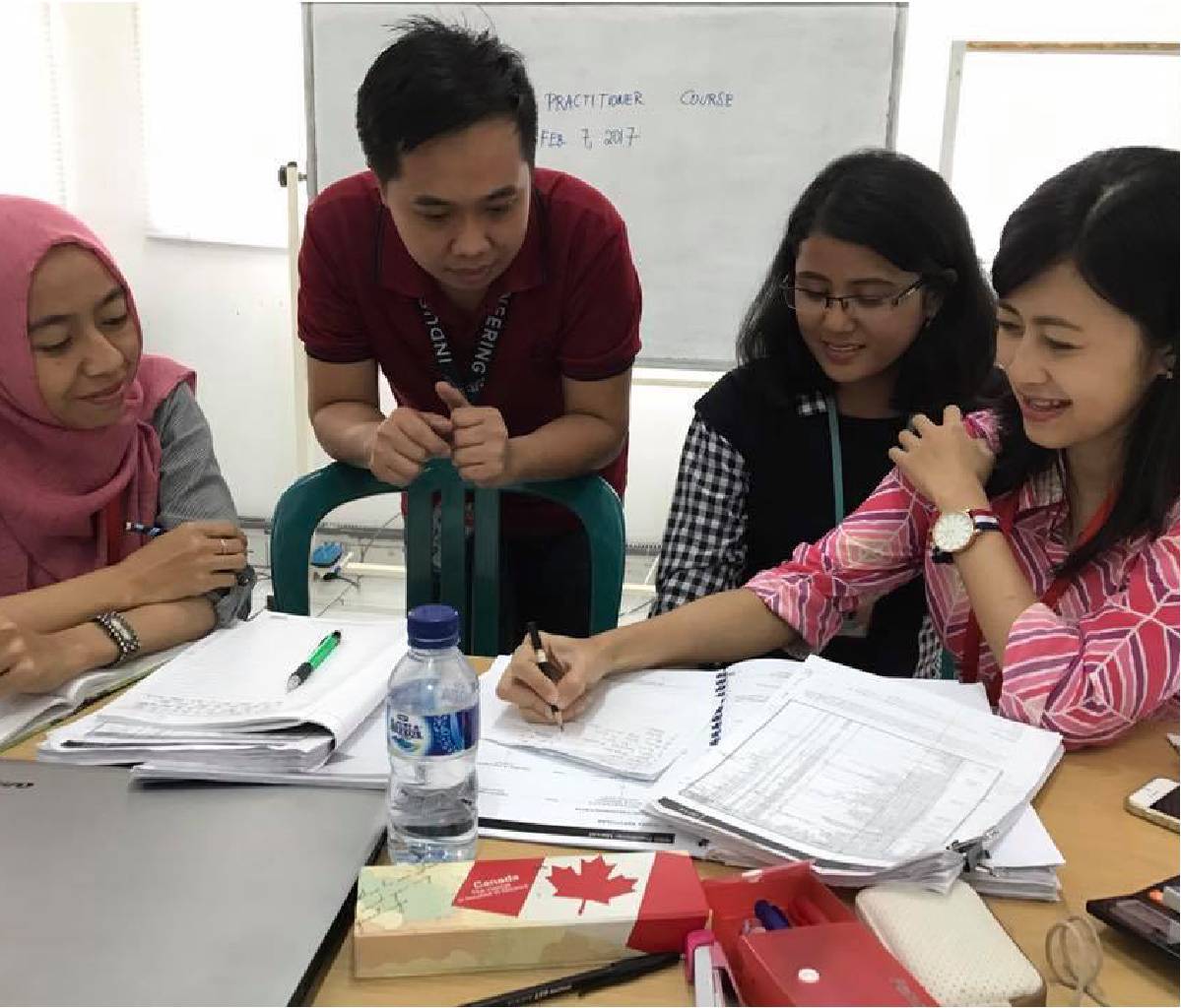 4 employees from PT. Sumbiri looking at calculations on piece of paper