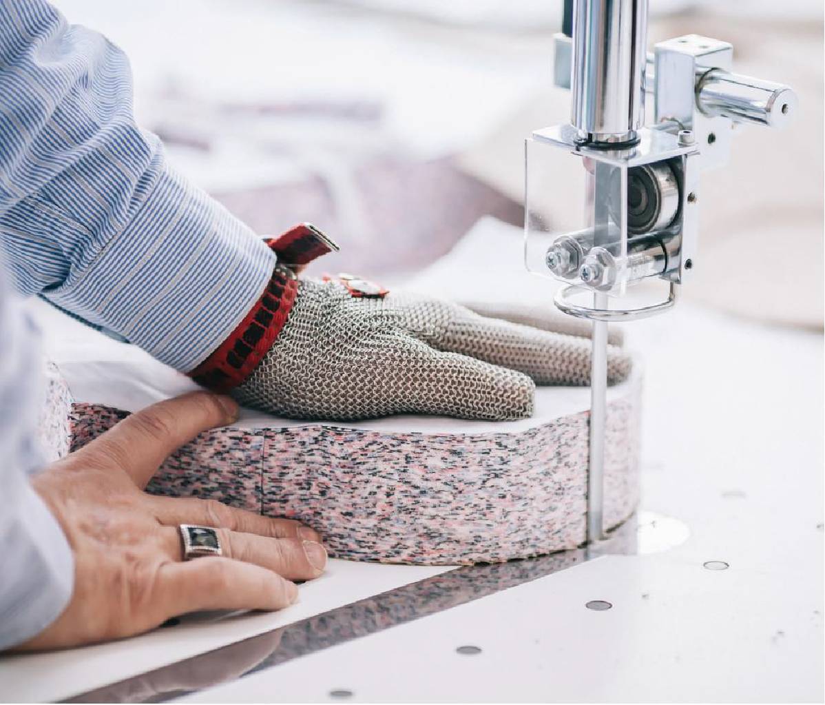 Man wearing safety glove cutting colourful fabric with a cutting machine