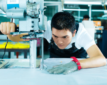Fabric cutting operator wearing safety glove in a garment factory