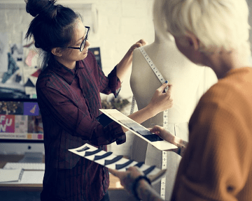 2 名女性时装设计师正在测量模特
