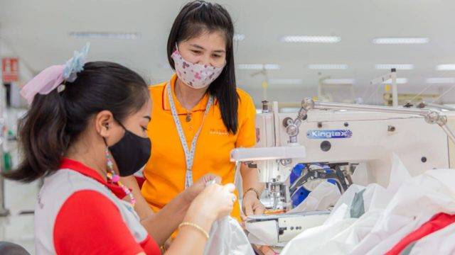 Female Hi-Tech seamstress being observed on a sewing machine by another female Hi-tech worker