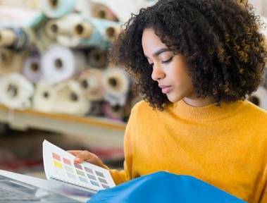 Lady wearing yellow jumper looking at fabric swatches in a fabric warehouse