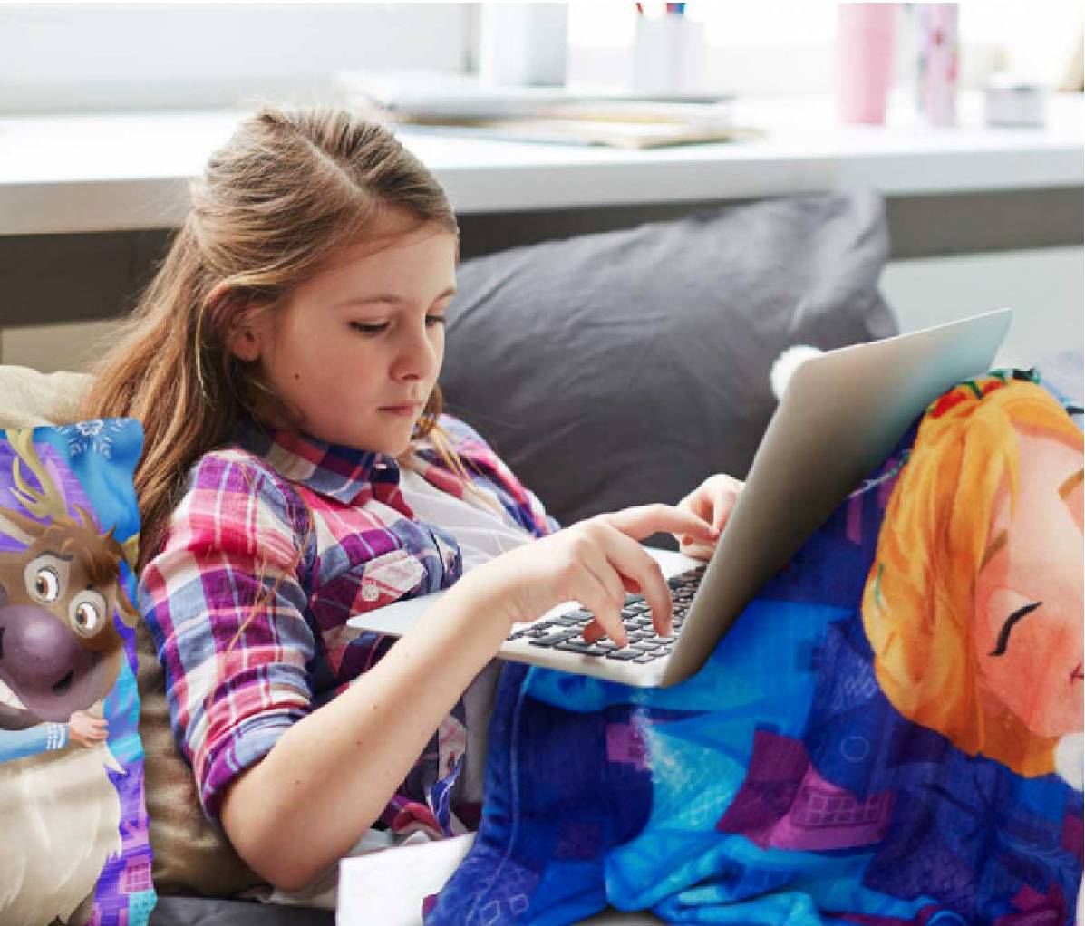 Young girl on laptop in Disney bedding
