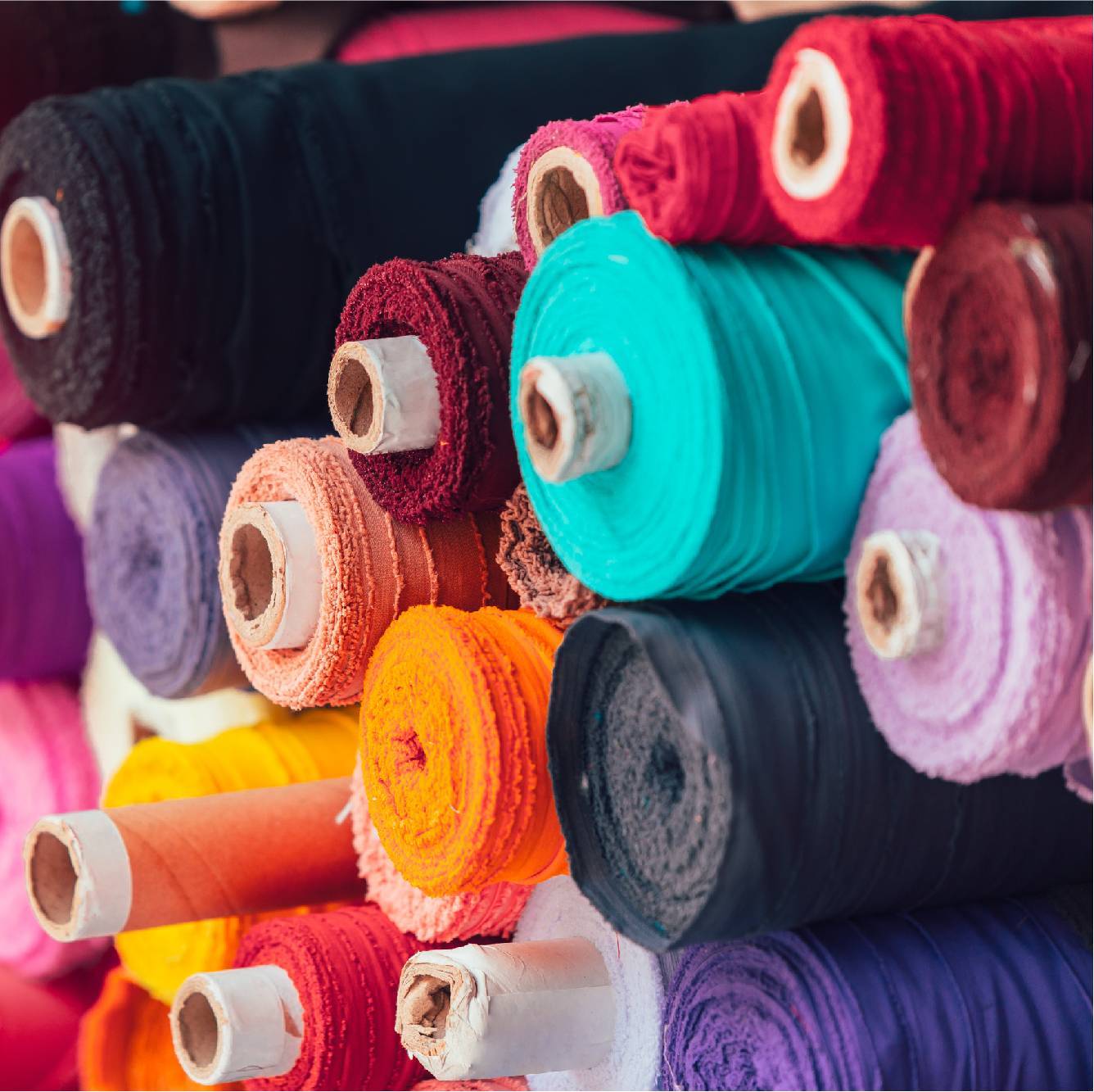 Rolls of colourful fabric in a pile