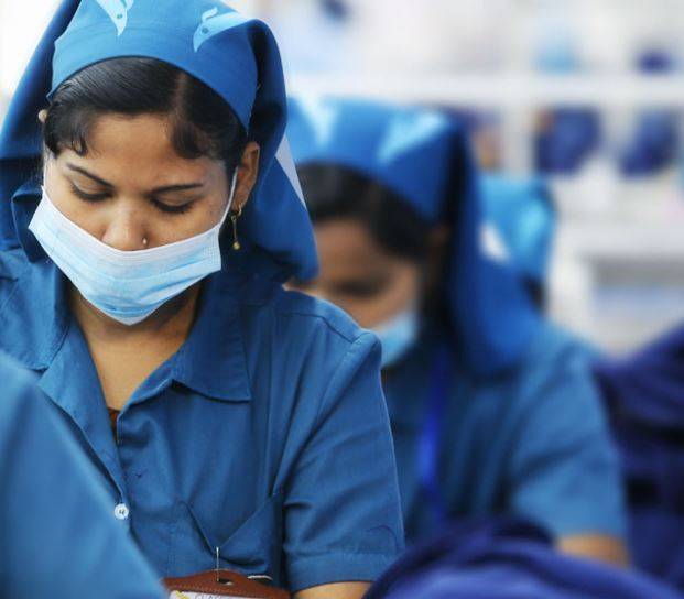 Woman in blue outfit working on a sewing machine